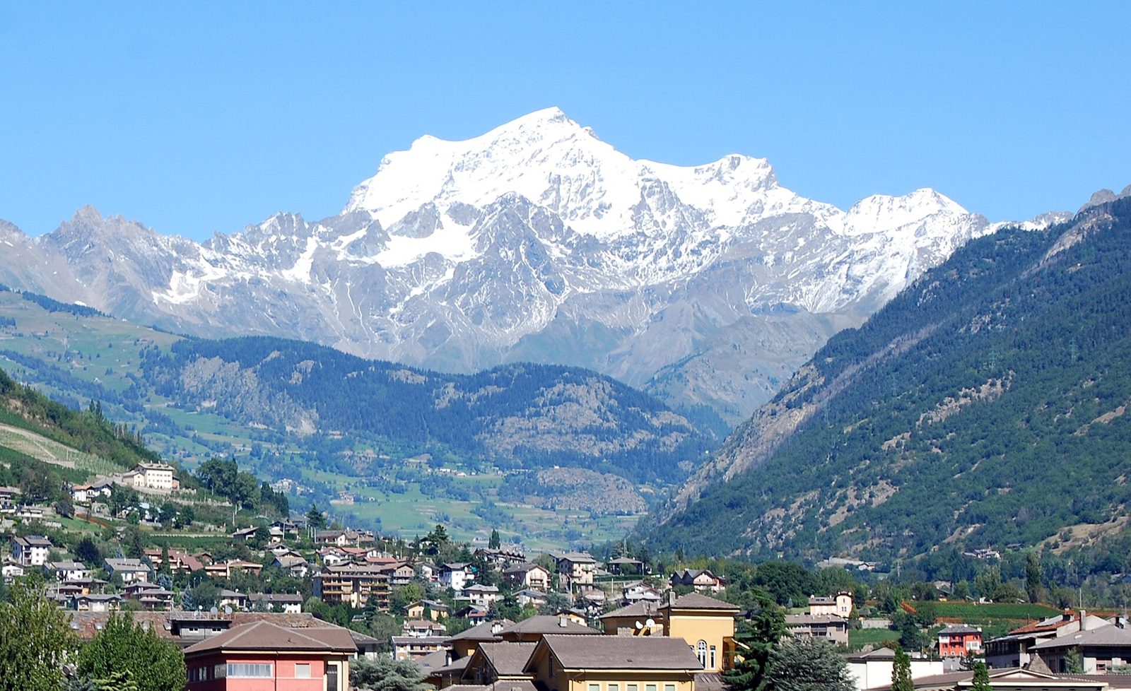 Il massiccio innevato del Grand Combin visto da Aosta, sopra le colline boscose della valle del Gran San Bernardo